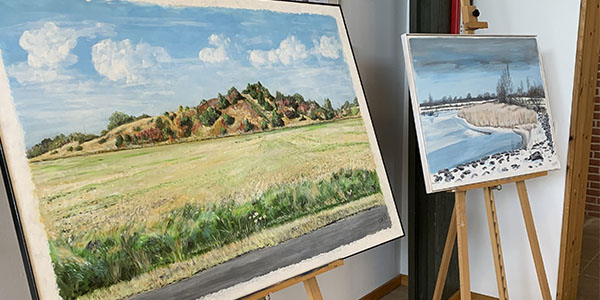 De to malerier af henholdsvis et grønt landskab i landsbyen og en vinterdag i havnen.